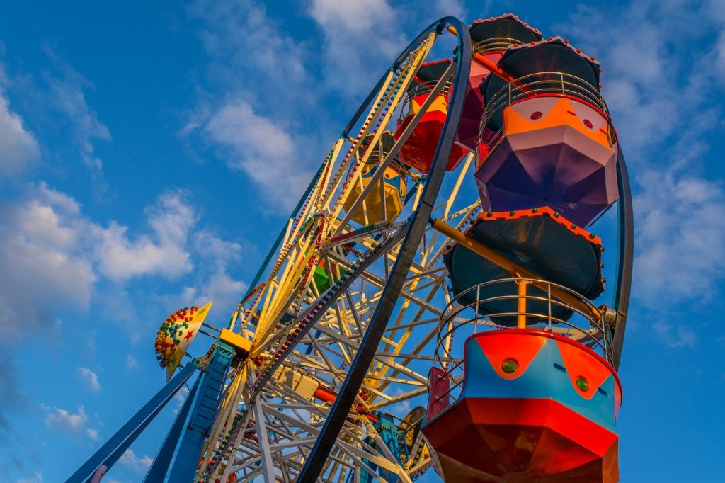 A colorful and festive ferris wheel against a blue sky.